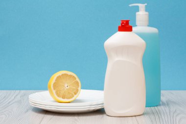 Döşeme Temizleyici, bulaşık deterjanı, cam ve plastik şişe temiz tabak ve mavi zemin üzerine limon. Yıkama ve Temizleme kavramı.