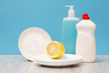 Döşeme Temizleyici, bulaşık deterjanı, cam ve plastik şişe temiz tabak ve mavi zemin üzerine limon. Yıkama ve Temizleme kavramı.
