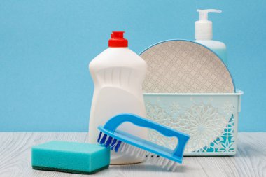 Plastik şişe bulaşık deterjanı, cam ve döşeme temizleyici, tabaklar sepet, fırça ve sünger mavi zemin üzerine temiz. Yıkama ve Temizleme kavramı.