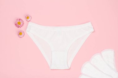 Güzel beyaz külot Sıhhi Peçete üzerinde pembe bir arka plan ile. Kadın iç çamaşırı ayarlayın. Üstten görünüm.