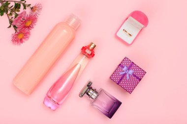 Hediye kutusu, şişe parfüm, şampuan ve kutusunda pembe bir arka plan üzerinde altın yüzük. Kadın kozmetik ve aksesuarları. Üstten görünüm.