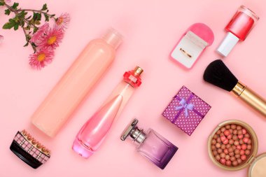 Hediye kutusu, şişe parfüm ve şampuan, hairgrip, altın yüzük kutusu, tırnak cilası, toz pembe bir arka plan üzerinde fırça ile. Kadın kozmetik ve aksesuarları. Üstten görünüm.