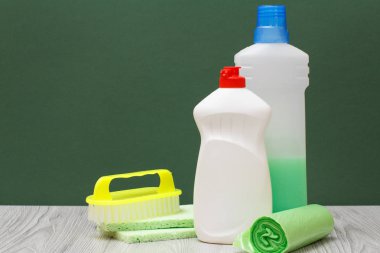 Bulaşık deterjanı, mikrodalga fırın ve soba, fırça, sünger ve çöp torbaları üzerinde yeşil arka plan için deterjan plastik şişe. Yıkama ve Temizleme kavramı.