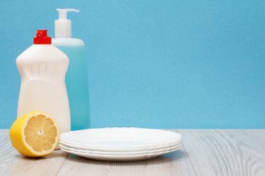 Döşeme Temizleyici, bulaşık deterjanı, cam ve plastik şişe temiz tabak ve mavi zemin üzerine limon. Yıkama ve Temizleme kavramı.