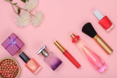Hediye kutusu, şişe parfüm, ruj, fırça ve pembe bir arka plan üzerinde çiçek tozu, tırnak cilası. Kadın kozmetik ve aksesuarları. Üstten görünüm.