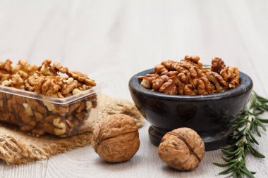 Soyulmuş ve soyulmamış ceviz taş kase ve Plastik Konteyner ile yas ve biberiye ahşap arka plan üzerinde. Yararlı besleyici protein ürün. Sığ derinlik-in tarla.