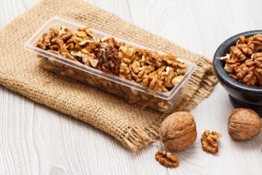 Soyulmuş Ceviz Plastik Konteyner ve çul ahşap zemin ile taş kase. Yararlı besleyici protein ürün. Üstten görünüm.