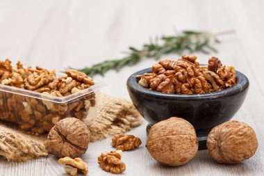 Soyulmuş ve soyulmamış ceviz taş kase ve Plastik Konteyner ile yas ve biberiye ahşap arka plan üzerinde. Yararlı besleyici protein ürün. Sığ derinlik-in tarla.