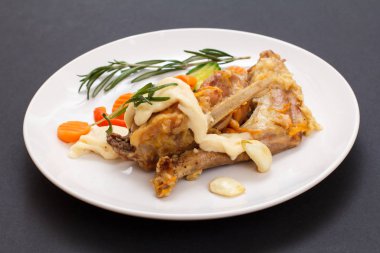 Tavşan bacağı bechamel sauce seramik bir tabakta sebze ile ve biberiye siyah arka plan üzerine beyaz şarapla pişirdim. Diyet tavşan et fırında pişmiş.