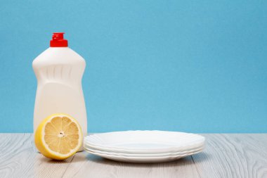 Plastik şişe bulaşık sıvı, temiz tabak ve limon ahşap panoları ve kopya alanı ile mavi arka plan. Yıkama ve Temizleme kavramı.