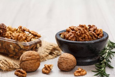 Soyulmuş ve soyulmamış ceviz taş kase ve Plastik Konteyner ile yas ve biberiye ahşap arka plan üzerinde. Yararlı besleyici protein ürün.