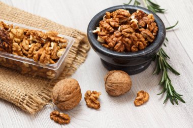 Soyulmuş ve soyulmamış ceviz taş kase ve Plastik Konteyner ile yas ve biberiye ahşap arka plan üzerinde. Yararlı besleyici protein ürün. Üstten görünüm.