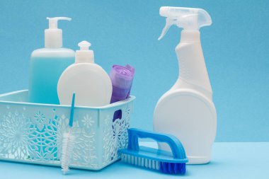Bulaşık deterjanı, plastik şişe cam ve temizleyici, sepet ve fırçalar mavi arka plan üzerinde çöp torbaları döşeme. Yıkama ve Temizleme kavramı.