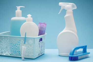 Bulaşık deterjanı, plastik şişe cam ve temizleyici, sepet ve fırçalar mavi arka plan üzerinde çöp torbaları döşeme. Yıkama ve Temizleme kavramı.