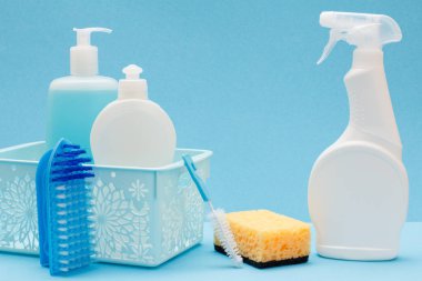 Sepetbulaşık sıvısı, cam ve fayans temizleyici plastik şişeler, fırçalar, mikrodalga fırınlar için sünger ve deterjan, mavi arka plan üzerinde soba. Yıkama ve temizleme konsepti.