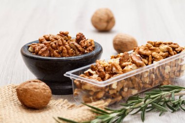 Soyulmuş ceviz taş kase ve Plastik Konteyner ile yas ve biberiye ahşap arka plan üzerinde. Yararlı besleyici protein ürün. Sığ derinlik-in tarla.