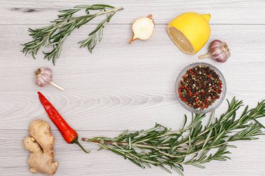 Et veya balık pişirme için malzemeler. Zencefil kökü, chili biber, sarımsak, soğan, limon, yenibahar biber cam kase ve biberiye ahşap arka plan üzerinde. Kopya alanı ile üstten görünüm.