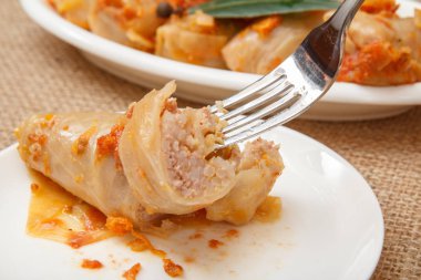 Ev yapımı lahana rulo dilim çatalla pirinç ve et beyaz tabak içinde yalan ile doldurulmuş.