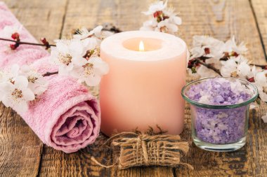 Sabun, deniz banyo yordamları için havlu ile cam kase içinde tuz ve yanan mum ile arka planda kayısı ağacı dalı çiçekli. Spa Ürünleri ve aksesuarları.