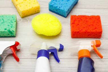 Su püskürtme ve renk sentetik süngerler gri ahşap arka plan üzerinde temizlik için. Araçları ve ekipmanları temizlik seti.