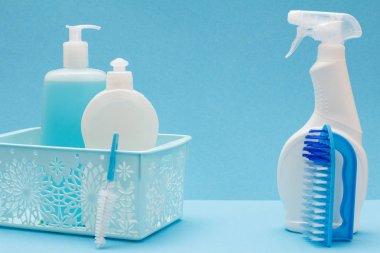 Sepette bulaşık sıvısı şişeleri ve mavi arka plan üzerinde fırçalar.