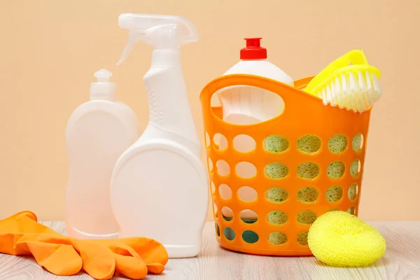Botellas de líquido lavavajillas, guante de goma, cesta y esponja sobre fondo beige . — Foto de Stock
