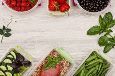 Haşlanmış karabuğday lapası ve et dilimleri, taze yeşillik ve meyve ile Plastik yemek hazırlık kapları.