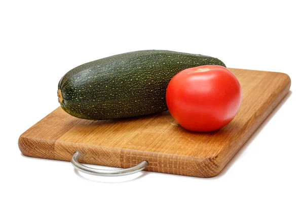 Tomato and zucchini on wooden cutting board. — Stock Photo, Image