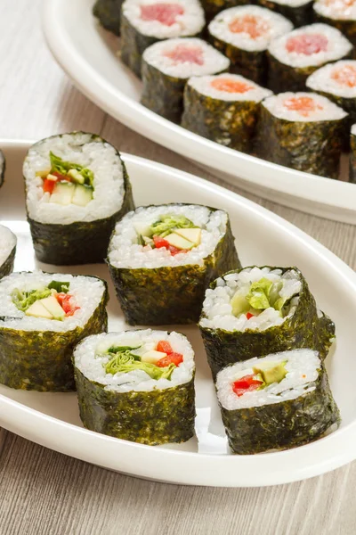 Diferentes rollos de sushi en platos de cerámica y palillos . — Foto de Stock