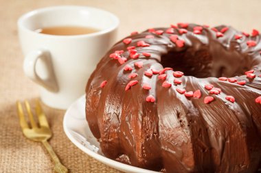 Ev yapımı çikolatalı kek küçük karamel kalpler ve çay fincan ile dekore.