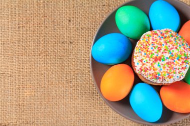 Paskalya pastası ve arka planda çuval bezi ile bir tabak üzerinde boyalı yumurta.