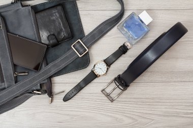 Gri arka planda cep telefonu ve kol saati olan erkekler için deri omuz çantası.