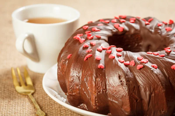Ev yapımı çikolatalı kek küçük karamel kalpler ve çay fincan ile dekore.
