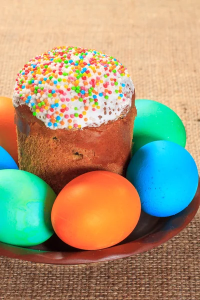 Torta pasquale e uova dipinte su un piatto con sacco sullo sfondo . — Foto Stock