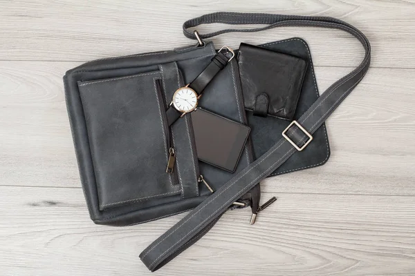 Bolso de hombro de cuero para hombres con teléfono móvil, reloj y billetera con fondo de madera gris — Foto de Stock