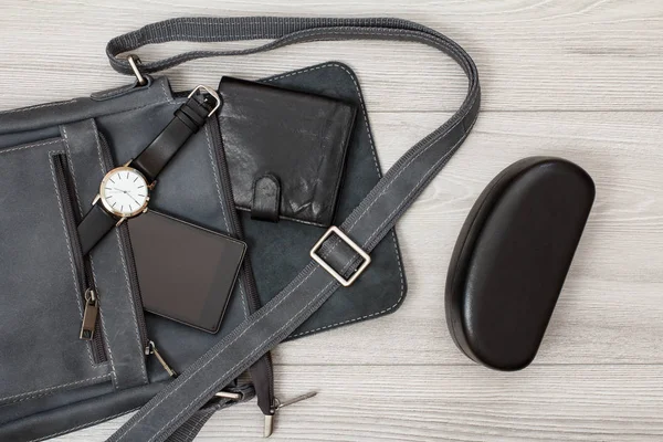 皮革肩包的男人与手机，手表和钱包上与灰色木制背景 — 图库照片
