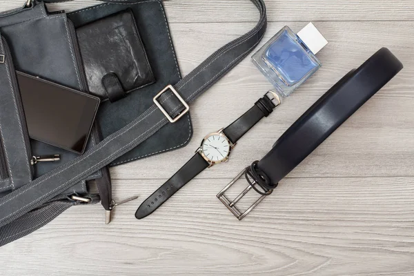 Gri arka planda cep telefonu ve kol saati olan erkekler için deri omuz çantası.