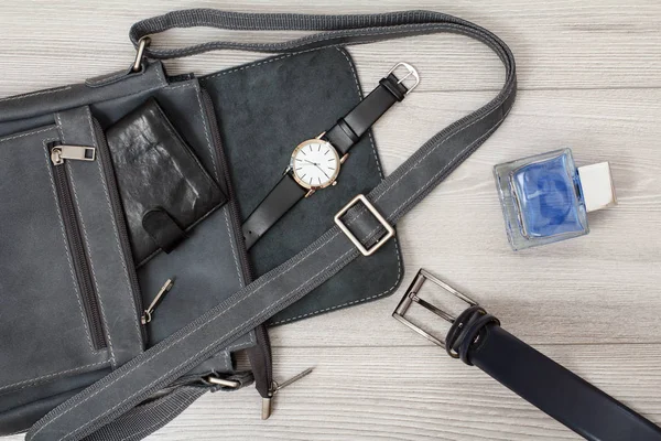 Bolso bandolera de cuero para hombre con billetera y reloj de pulsera sobre fondo gris . — Foto de Stock