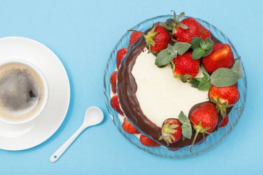 Cam tabakta taze çilek ve tabak kahve ile kahve ile dekore edilmiş ev yapımı çikolatalı kek.