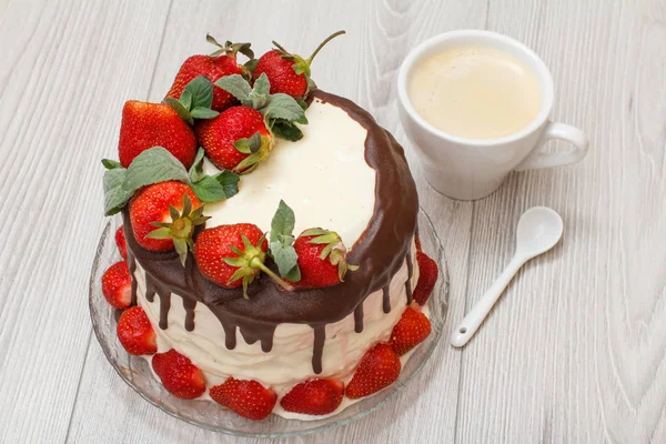 Домашний шоколадный торт, украшенный свежей клубникой на стеклянной тарелке и чашкой кофе — стоковое фото