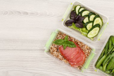 Yeşil bezelye, haşlanmış karabuğday lapası ve et dilimleri, taze salatalık ve salata ile Plastik yemek hazırlık kapları.