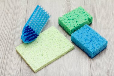 Ahşap tahtalarda temizlik için sentetik süngerler, mikrofiber peçete ve fırça.