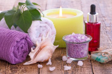 Sabun, yanan mum, deniz tuzu ile kase, aromatik yağ ile şişe, leylak çiçekler ve ahşap arka plan üzerinde havlu.