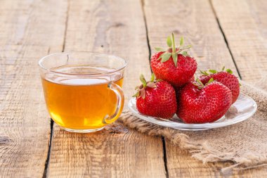 Cam kase yeşil çay ve kırmızı olgun çilek cam fincan.