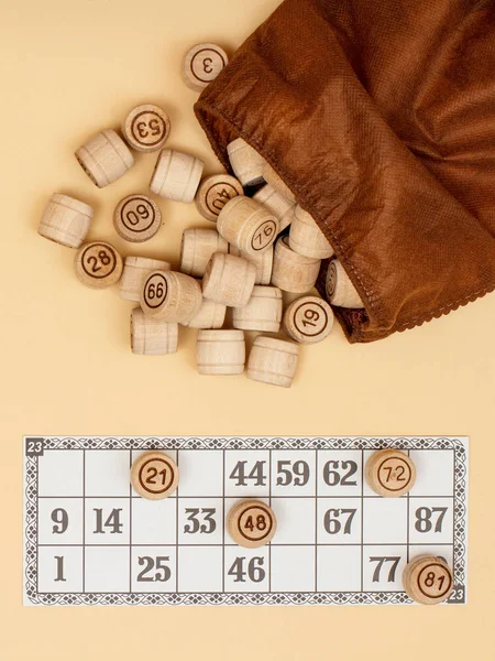 Barils de loto en bois avec sac et carte de jeu sur fond beige . — Photo