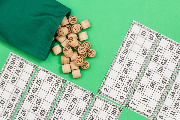 Barils de loto en bois avec sac et cartes de jeu sur fond vert — Photo