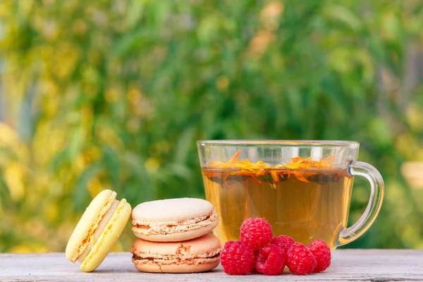 Cup of green tea, macaroons cakes and fresh raspberries. — Stock Photo, Image