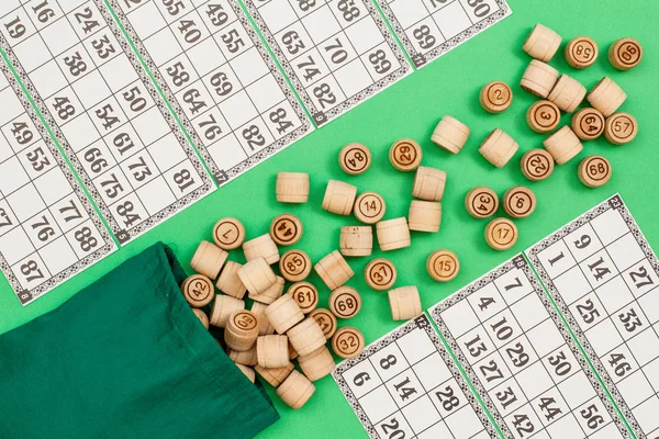 Barils de loto en bois avec sac et cartes de jeu sur fond vert — Photo