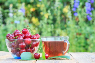 Cam kase ve çay fincan peduncles ile kırmızı olgun kiraz meyve.