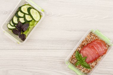 Haşlanmış karabuğday lapası, et dilimleri ve taze sebze ile plastik yemek hazırlama kapları.